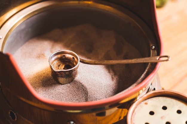 Voorbereiding van Turkse koffie in cezve op zand bij koffiestaaf