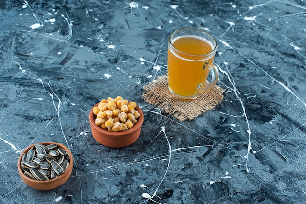 Voorgerechten in kommen naast een glas bier op textuur, op de blauwe tafel.