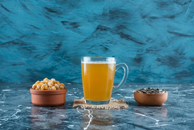 Voorgerechten in kommen naast een glas bier op textuur, op de blauwe tafel.