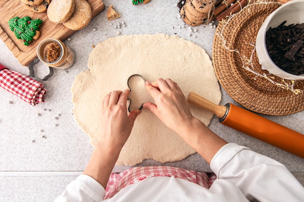 Gratis foto vorm voor kerstkoekjes in vrouwelijke handen tegen de achtergrond van deeg