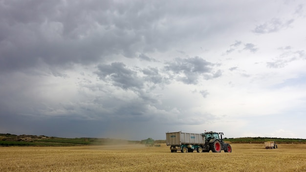 Gratis foto vrachtwagens op het veld op een bewolkte dag tijdens de oogsttijd