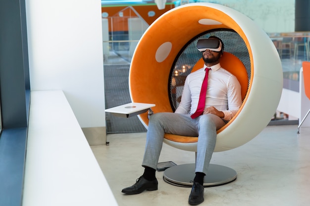 Vreedzame zakenman die in VR-hoofdtelefoon van virtuele video genieten