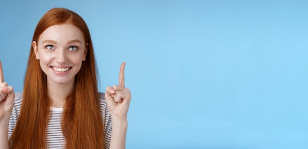 Vreugdevol nieuwsgierig vermaakt gelukkig vermaakt roodharig mooi meisje staren wijzend naar boven glimlachend goedkeuring