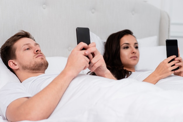 Vriend en vriendin controleren hun telefoon na het wakker worden