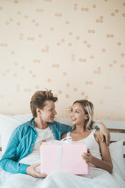 Vriend verras zijn vriendin met geschenkdoos op het bed