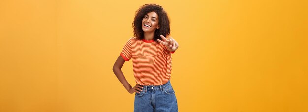 Vriendelijk zorgeloos en gelukkig knap lang Afrikaans Amerikaans vrouwelijk model met gekrulde kapselgreep