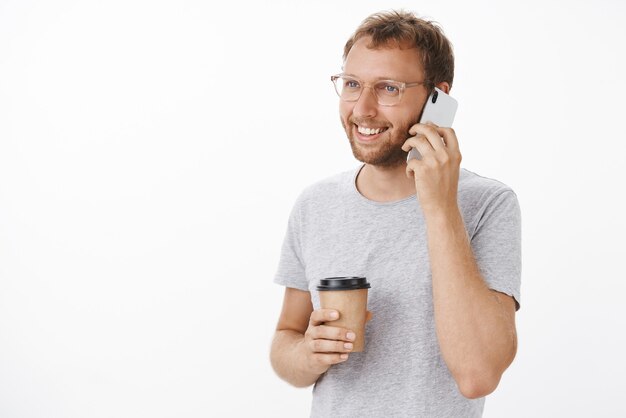 Vriendelijke gelukkige kerel die telefonisch spreekt en koffie drinkt