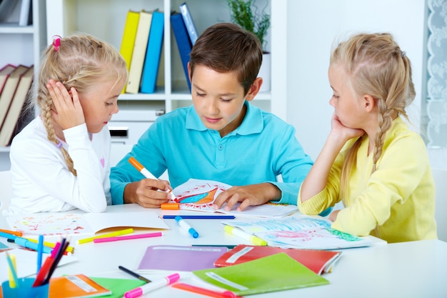 Gratis foto vriendelijke jongen zittend op zijn bureau