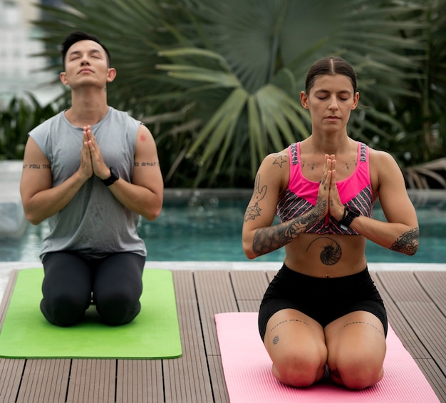 Gratis foto vrienden beoefenen samen yoga buiten bij het zwembad