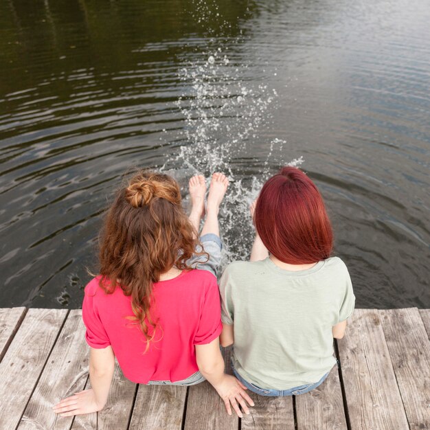 Vrienden die aan de kade blijven en met hun voeten water spetteren +