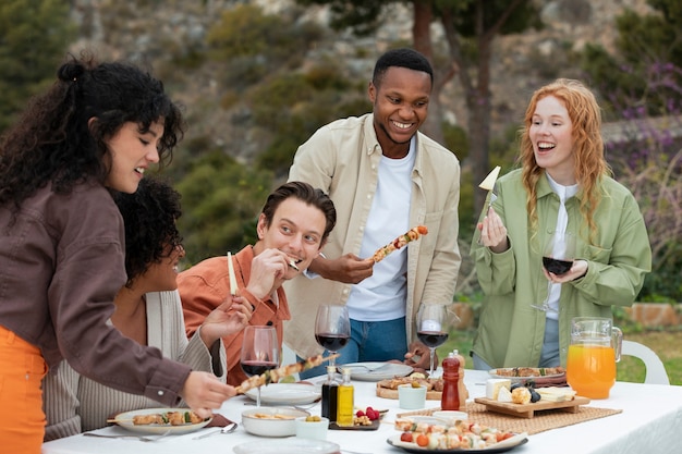 Vrienden die barbecue en kaas eten tijdens een buitenfeest