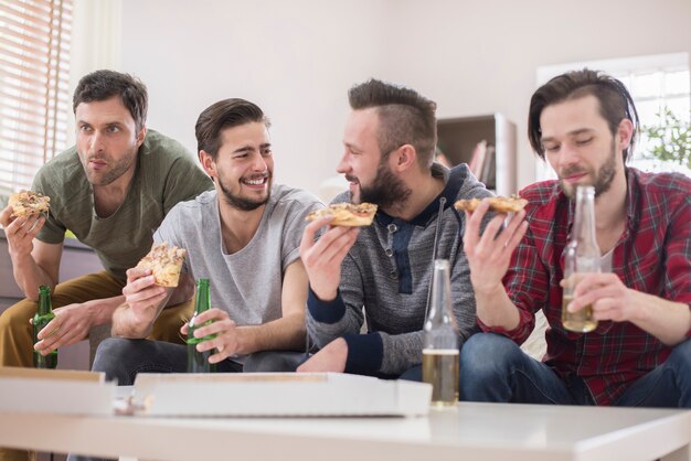 Vrienden die bier drinken en pizza eten