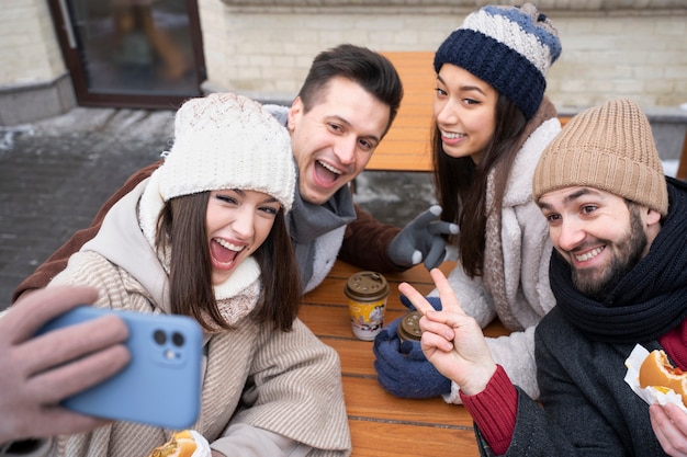 Gratis foto vrienden die een selfie maken onder het genot van koffie en hamburgers