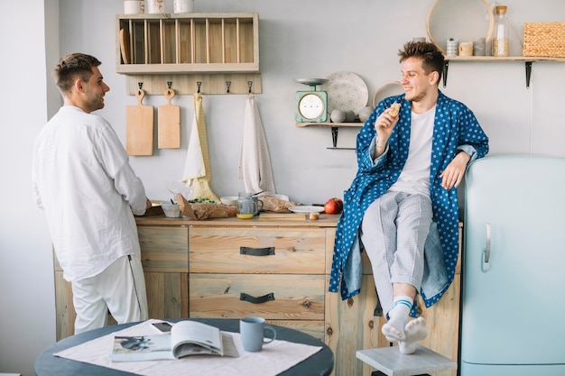 Vrienden die elkaar bekijken terwijl het eten van voedsel in keuken