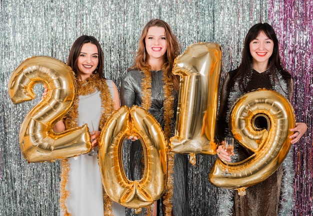 Vrienden die met gouden ballons bij een nieuwe jaarpartij stellen