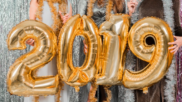 Vrienden die met gouden ballons bij een nieuwe jaarpartij stellen