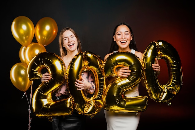 Vrienden die met gouden ballons bij nieuwe jarenpartij stellen