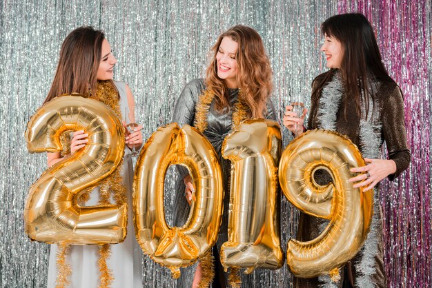 Vrienden die met gouden ballons stellen bij de nieuwe partijvrienden die met gouden ballons bij een nieuwe jaarpartij stellen