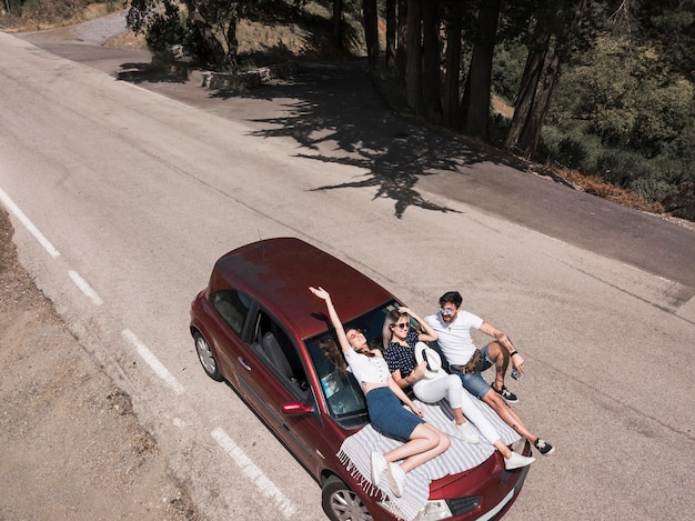 Gratis foto vrienden die op autokap ontspannen over de weg