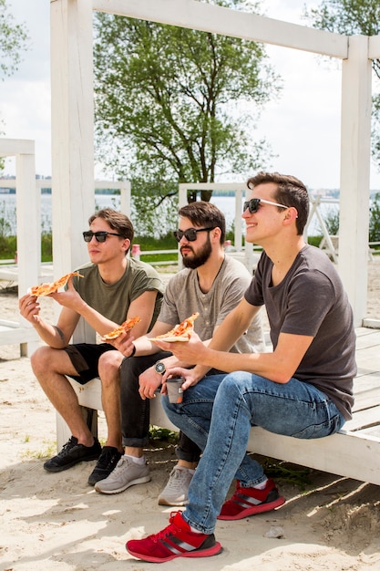 Vrienden die pizza op strand eten