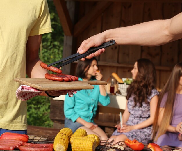 Vrienden die plezier hebben en voedsel grillen in het kamp