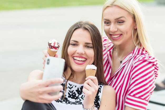 Vrienden die selfie terwijl het eten van roomijskegel met cellphone nemen