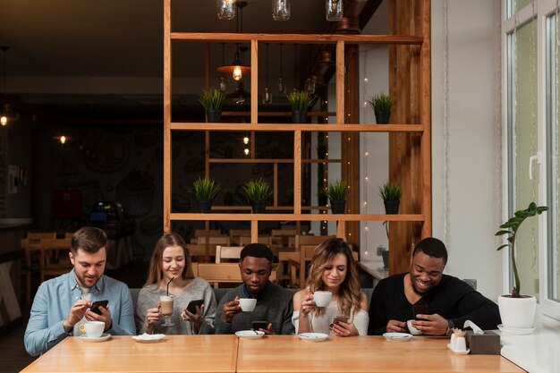 Vrienden in restaurant met behulp van telefoons