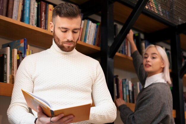 Vrienden kijken naar boek in een bibliotheek