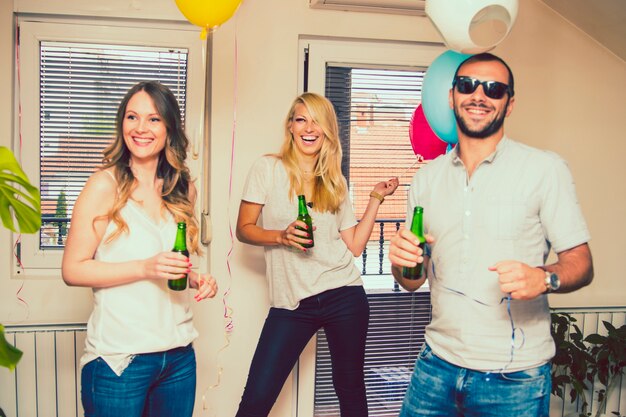 Gratis foto vrienden lachen op feestje met een fles bier