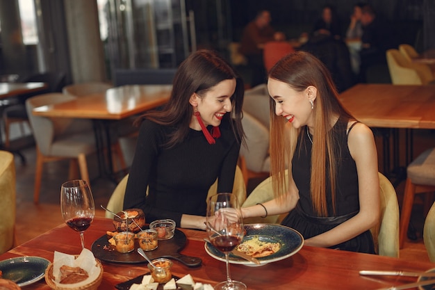 Vrienden praten en plezier hebben tijdens het etentje. Elegant geklede vrouwen van mensen die aan het dineren zijn.