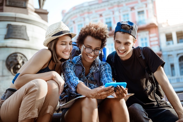 Vrienden reizigers met rugzakken glimlachen, selfie maken, zitten in de buurt van zicht.