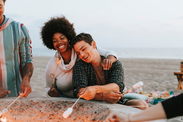 Vrienden roosteren marshmallows op het strand