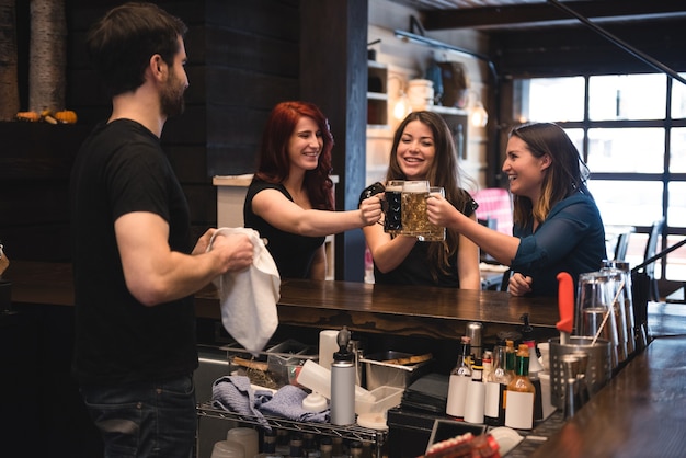 Vrienden roosteren met bierglazen aan toog