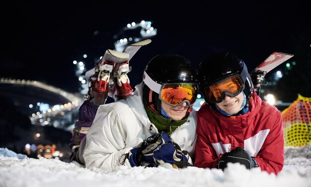Vrienden skiërs die plezier hebben in het skigebied in de bergen in de winter 's nachts skiën
