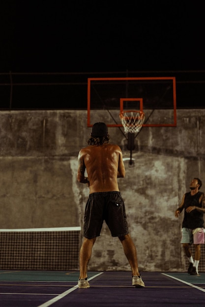 Gratis foto vrienden spelen basketbal. jonge mannen spelen basketbal op straat.