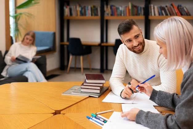 Gratis foto vrienden studeren met notebooks in een bibliotheek