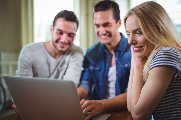 Vrienden zitten aan tafel en met behulp van laptop in cafÃ ©