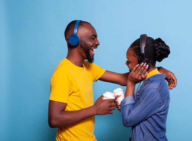 Vriendin en vriend zingen en hebben plezier met een liedje op een koptelefoon, genietend van afspeellijstmuziek. vrolijk paar luisteren naar mp3-geluid op headset, glimlachen en elkaar in de studio.