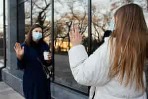 Gratis foto vriendinnen dragen maskers en zwaaien