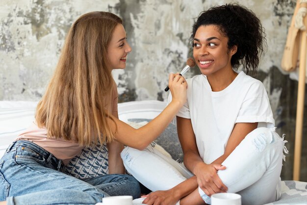 Vriendinnen helpen elkaar met make-up in bed