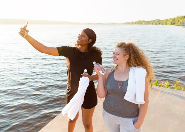 Vriendinnen nemen selfie samen tijdens het sporten aan het meer