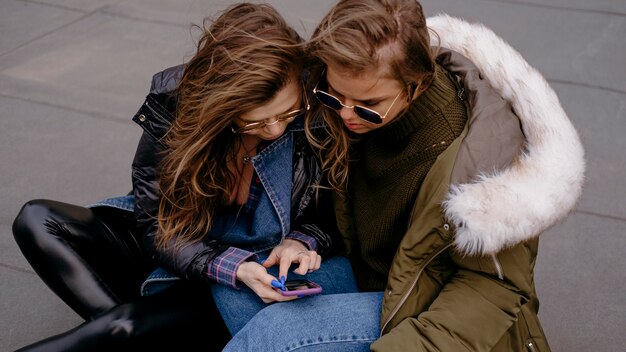 Gratis foto vriendinnen samen plezier buitenshuis met smartphone