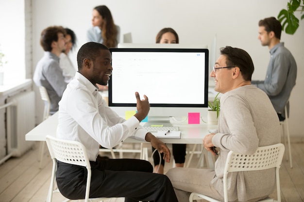 Vriendschappelijke glimlachende diverse mannelijke collega&#39;s die prettig gesprek hebben op het werk