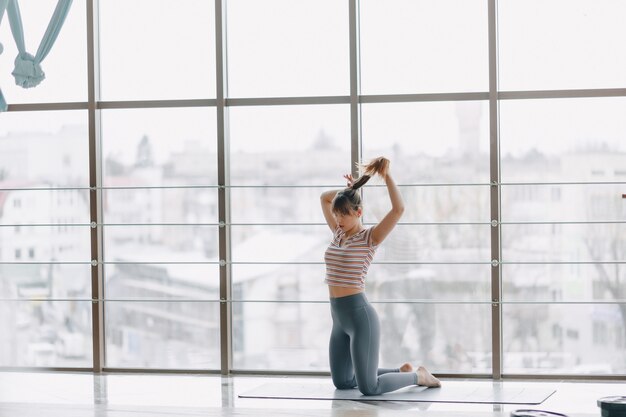 Vrij aantrekkelijk meisje dat yoga in een heldere ruimte doet