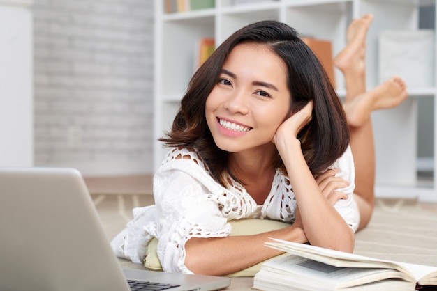 Vrij Aziatisch Meisje dat op Vloer met Boek en Laptop voor haar ligt