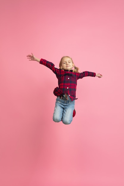 Vrij en gelukkig, vliegend, hoog springend. Portret van het blanke meisje op roze muur. Mooi model met blond haar. Concept van menselijke emoties, gezichtsuitdrukking, verkoop, advertentie, jeugd, jeugd.