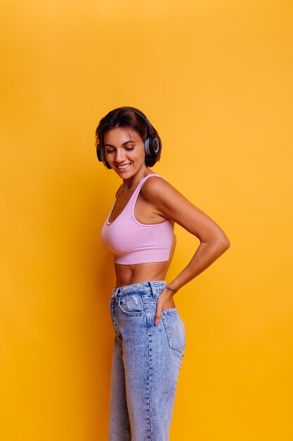 Vrij gebruinde vrouw met perfecte abs hoofdtelefoon dragen, dansen en luisteren naar muziek