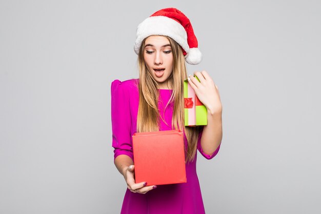 Vrij glimlachend grappig gelukkig meisje in korte roze jurk en nieuwjaarshoed houden kartonnen doos verrassing in haar handen