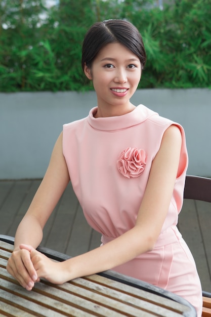 Gratis foto vrij glimlachende jonge aziatische vrouw bij cafe table