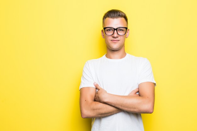 Vrij jonge jongen houdt zijn armen gekruist gekleed in wit t-shirt en transparante bril